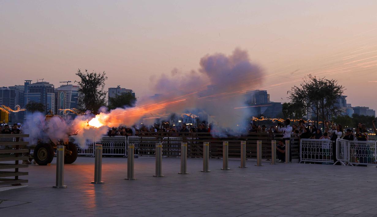 Dentuman meriam Ramadan, atau dikenal sebagai Madfa al-Iftar, merupakan tradisi turun-temurun yang masih dilestarikan oleh Angkatan Bersenjata Qatar untuk menandai waktu berbuka puasa. Tampak dalam foto, Angkatan Bersenjata Qatar menembakkan meriam untuk menandai berakhirnya puasa harian selama bulan suci Ramadan di Pelabuhan Lama, Doha pada Selasa 24 Februari 2026. (Karim JAAFAR/AFP)