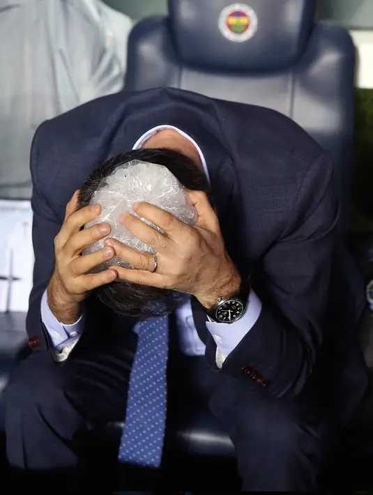 Pelatih Besiktas, Senol Gunes mengompres kepalanya setelah terkena lemparan benda tajam dari tribun penonton pada semifinal Piala Turki melawan Fenerbahce di Istanbul, Kamis (19/4). Gunes harus dilarikan ke rumah sakit dan menerima lima jahitan. (AP)