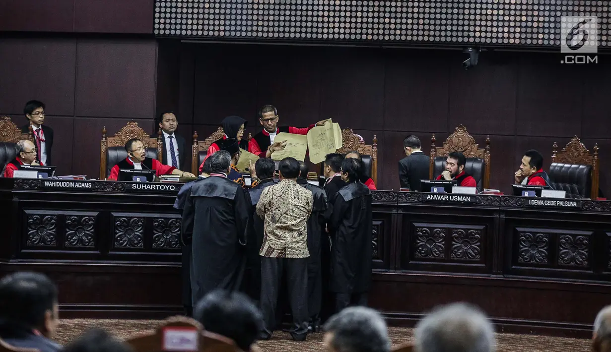 Majelis Hakim mengecek amplop yang dibawa Komisioner KPU, Hasyim Asyari disaksikan tim kuasa hukum pasangan Prabowo-Sandiaga selama sidang lanjutan sengketa pilpres 2019 di Gedung MK, Jakarta, Kamis (20/6/2019). Selain itu juga tidak ada bekas lem pada amplop itu. (Liputan6.com/Faizal Fanani)