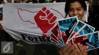 Salah satu peserta memperlihatkan brosur saat aksi di Bundaran Hotel Indonesia, Jakarta, Minggu (4/9). Mereka menyerukan Tolak Reklamasi Teluk Benoa. (Liputan6.com/Johan Tallo)