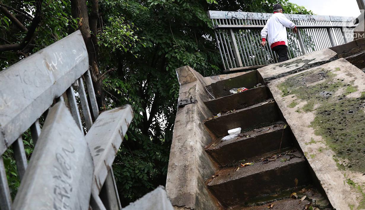 Pejalan kaki melintasi JPO yang rusak di Terminal Kampung Rambutan, Jakarta, Senin (28/1). Kondisi JPO yang sebagian pagar pembatasnya rusak tersebut membahayakan pejalan kaki apabila tidak segera diperbaiki. (Liputan6.com/Immanuel Antonius)