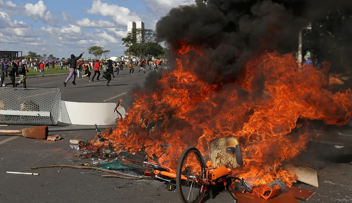 Demonstran membakar kursi yang diambil dari gedung Kementerian Pertanian dalam unjuk rasa anti-pemerintah di Brasilia, Brasil, Rabu (24/5). Unjuk rasa yang semula damai berubah rusuh setelah terjadi bentrokan dengan polisi. (AP Photo/Eraldo Peres)