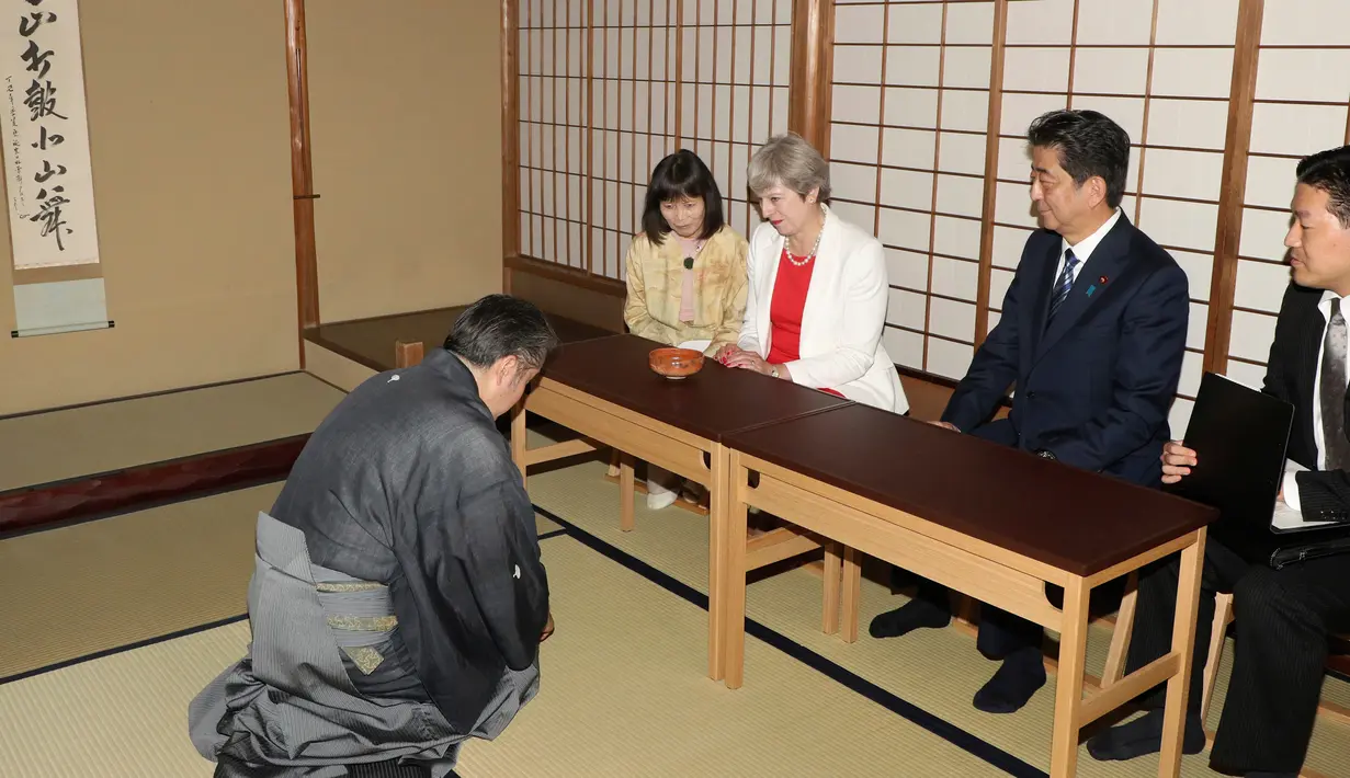 PM Theresa May (tengah) saat mengikuti upacara minum teh bersama PM Jepang Shinzo Abe di Kyoto, Jepang (30/8). Kunjungan tersebut membicarakan perjanjian bilateral setelah Inggris meninggalkan Uni Eropa.(Hirofumi Yamamoto/Japan Pool Photo via AP)