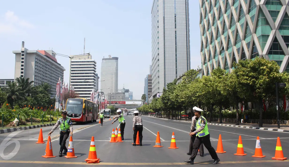 Seorang petugas kepolisian terlihat mengatur ruas jalan sekitar patung kuda, Jakarta, Selasa (1/8/2015). Hari ini ratusan buruh berkumpul di Patung Kuda untuk mengadakan aksi unjuk rasa hingga ke Istana Merdeka. (Liputan6.com/Gempur M Surya)
