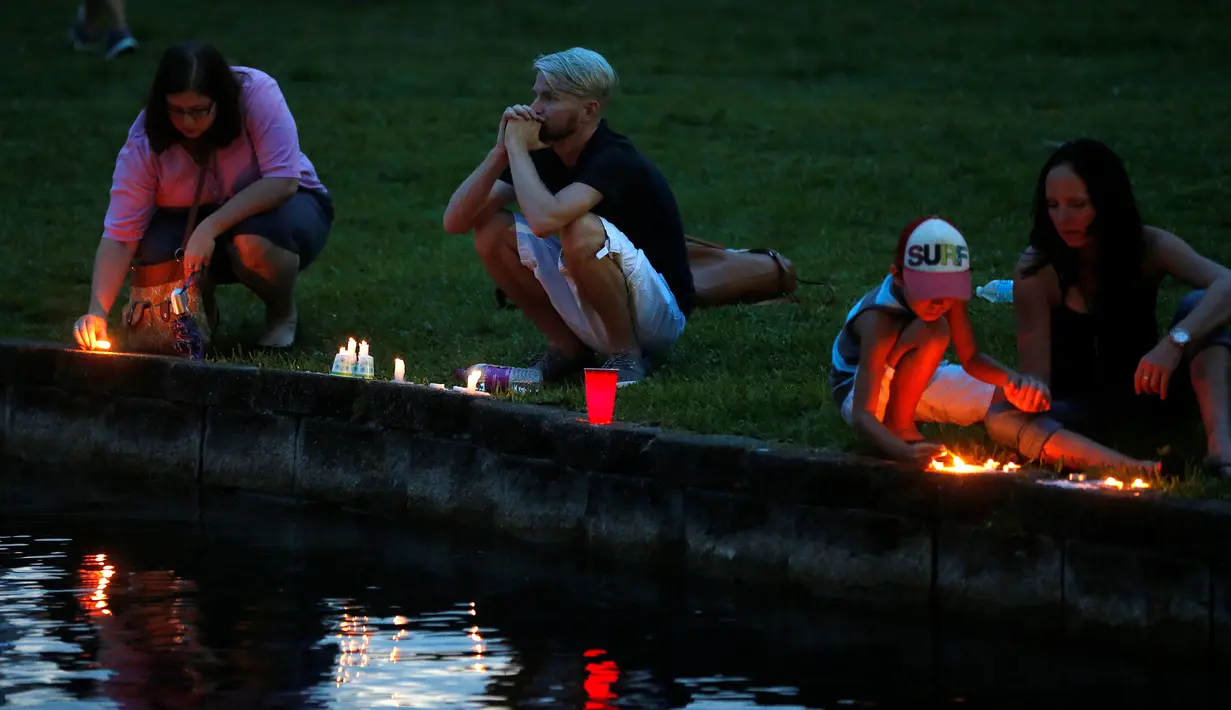 Sejumlah orang menyalakan lilin untuk mengenang korban penembakan di Pulse, klub malam khusus kaum gay di Orlando, Florida, AS, Minggu (12/6). 50 orang tewas dan 53 terluka akibat penembakan yang dilakukan Omar Saddiqui Mateen. (REUTERS/Carlo Allegri)