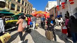 Pelancong dari China daratan berjalan di sekitar Lapangan Senado, tujuan wisata di Makau, 18 Januari 2022. Ledakan pariwisata China yang diharapkan selama liburan Tahun Baru Imlek minggu depan tampaknya akan lebih cepat terjadi. (AP Photo/Kanis Leung)