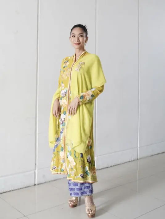 Happy Salma mengenakan kebaya panjang brokat warna kuning dipadukan selendang dan kain biru. [Instagram/@happysalma]