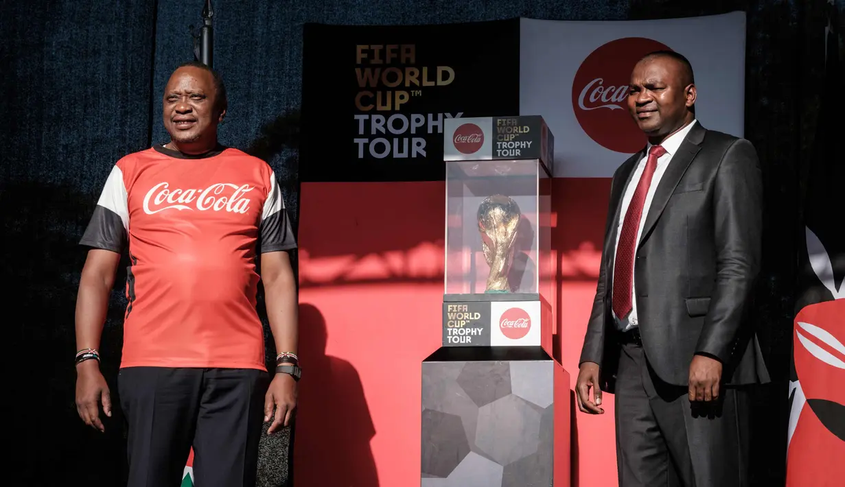 Presiden Kenya Uhuru Kenyatta (kiri) dan Menteri Olahraga Rashid Achersa berpose dengan trofi Piala Dunia FIFA selama tur dunia di State House di Nairobi (26/2). (AFP Photo/Yasuyoshi Chiba)