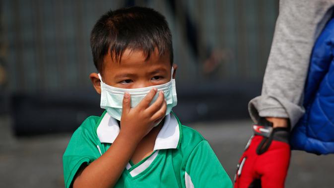 Seorang anak laki-laki mengenakan masker saat dijemput orang tuanya di Bangkok, Thailand (30/1). Thailand sedang menghadapi persoalan polusi udara terburuk yang pernah terjadi di negera tersebut. (AP Photo/Sakchai Lalit)