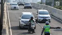 Petugas kepolisian memberhentikan pengemudi ojek online yang melintasi JLNT Kampung Melayu-Tanah Abang, Jakarta, Selasa (25/7). Polisi terus merazia kendaraan roda dua yang melanggar rambu larangan melintas di JLNT tersebut. (Liputan6.com/Faizal Fanani)