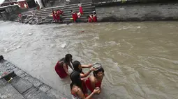 Sejumlah wanita Hindu Nepal mandi suci di sungai Bagmati selama festival Rishi Panchami di Kathmandu (3/9/2019). Di festival ini para wanita berpuasa di siang hari dan berdoa untuk umur panjang untuk suami mereka. (AFP Photo/Prakash Mathema)