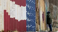 Seorang pria melihat melalui pagar perbatasan Amerika Serikat (AS) dengan Meksiko di Playas de Tijuana, Baja California, Meksiko, Minggu (11/3). Pagar perbatasan terbuat dari struktur baja setinggi sembilan meter. (GUILLERMO ARIAS/AFP)