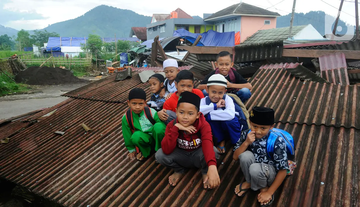 Murid-murid korban gempa belajar berpose usai sekolah di halaman sekolah di SDN Gintung, Mangunkerta, Cianjur, Jumat (23/12/2022). Lebih dari sebulan sejak musibah gempa bumi 5,2 SR sejumlah murid sekolah di Cianjur masih belajar pada tenda darurat. (merdeka.com/Arie Basuki)