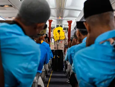 Para calon jemaah haji Indonesia menyimak cara menggunakan jaket penyelamat dari awak kabin di dalam pesawat Boeing 717 yang sudah tidak digunakan lagi selama sesi pelatihan keselamatan pra-keberangkatan di pusat embarkasi haji Banda Aceh pada Kamis 14 Mei 2026. (CHAIDEER MAHYUDDIN/AFP)