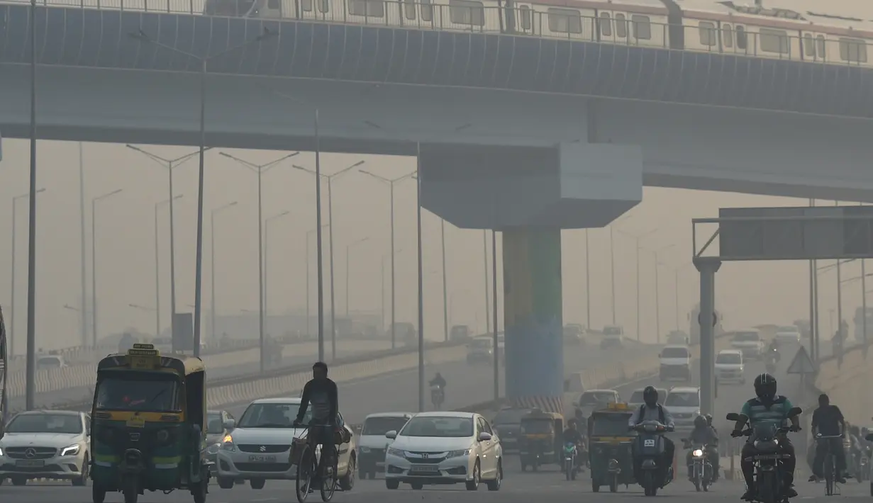 Sejumlah kendaraan melintas di tengah kondisi kabut asap tebal di New Delhi (30/10). Tingkat kabut melonjak selama musim dingin di Delhi, ketika kualitas udara sering melampaui tingkat aman Organisasi Kesehatan Dunia. (AFP Photo/Prakash Singh)