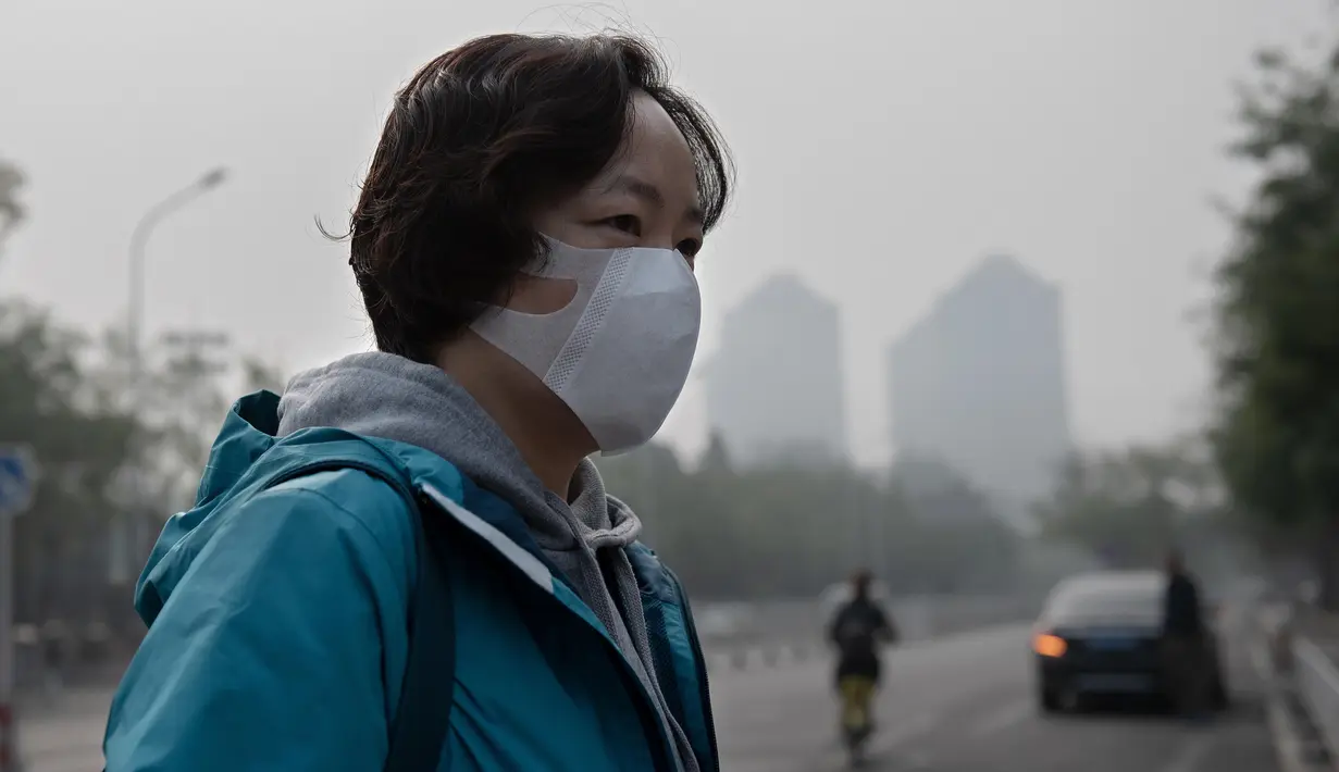 Seorang wanita beraktivitas mengenakan masker pelindung untuk menghindari polusi udara buruk di Beijing (22/10). (AFP Photo/Nicolas Asfaouri)