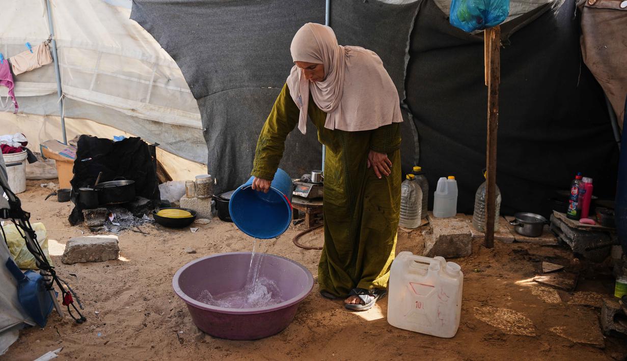 Meski truk bantuan mulai masuk secara bertahap sejak kesepakatan gencatan senjata antara Israel dan Hamas diberlakukan, volume bantuan seringkali belum mencukupi kebutuhan ribuan warga yang menetap di kamp darurat. Tampak dalam foto, pengungsi Palestina, Reem Abu Lahia, menggunakan air untuk mencuci pakaian di dalam tenda tempat tinggalnya di Khan Younis, Jalur Gaza Selatan, Kamis 30 April 2026. (AP Photo/Abdel Kareem Hana)