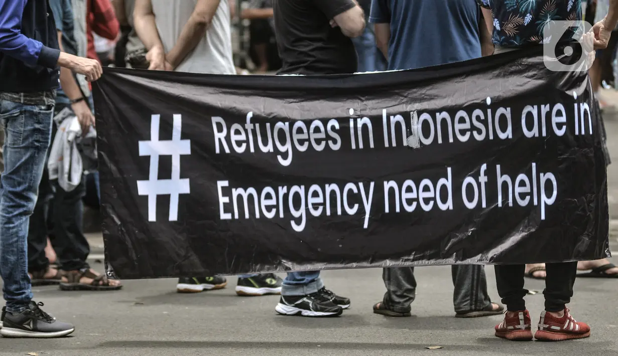 Pencari suaka membawa spanduk saat unjuk rasa di depan kantor UNHCR, Jakarta, Senin (14/12/2020). Mereka meminta agar proses perpindahan ke negara tujuan dipercepat setelah adanya tiga orang pengungsi yang bunuh diri dalam dua minggu terakhir karena depresi. (merdeka.com/Iqbal Nugroho)