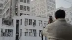 Seseorang mengambil foto gedung Derzhprom—sebuah gedung pencakar langit bersejarah Soviet—yang rusak setelah serangan rudal di Kharkiv pada 29 Oktober 2024. (Ivan SAMOILOV/AFP)