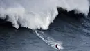 Peselancar asal Chili, Rafael Tapia beraksi saat ombak besar mengejarnya di Praia do Norte di Nazare, Portugal (19/11). Olahraga ini dilakukan dengan menggunakan sebuah papan sebagai alat untuk bermanuver di atas ombak. (AFP/Patricia De Melo Moreira)