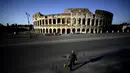 Seorang pria membawa anjingnya jalan-jalan di depan Colosseum, Roma, Italia, 3 April 2020. Menurut Departemen Perlindungan Sipil Italia pada 6 April 2020, jumlah kasus virus corona COVID-19 di negara tersebut menjadi 132.547 infeksi, 16.523 meninggal, dan 22.837 sembuh. (Filippo MONTEFORTE/AFP)