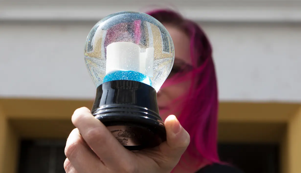 Anak perempuan pemilik perusahaan Original Vienna Snow Globes, Sabine Perzy II memperlihatkan bola salju berisi gulungan kertas toilet di Wina, Austria, pada 17 April 2020. Bola salju yang memiliki desain istimewa ini terinspirasi dari panic buying pada awal virus corona Covid-19. (ALEX HALADA/AFP)