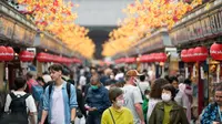 Turis melihat sekeliling saat berjalan di distrik hiburan Asakusa, Tokyo, Jepang, Senin (17/10/2022). Kawasan ini dipenuhi pejalan kaki yang melihat toko-toko suvenir yang mengarah ke kuil Buddha Sensoji yang terkenal di Tokyo. (AP Photo/Hiro Komae)