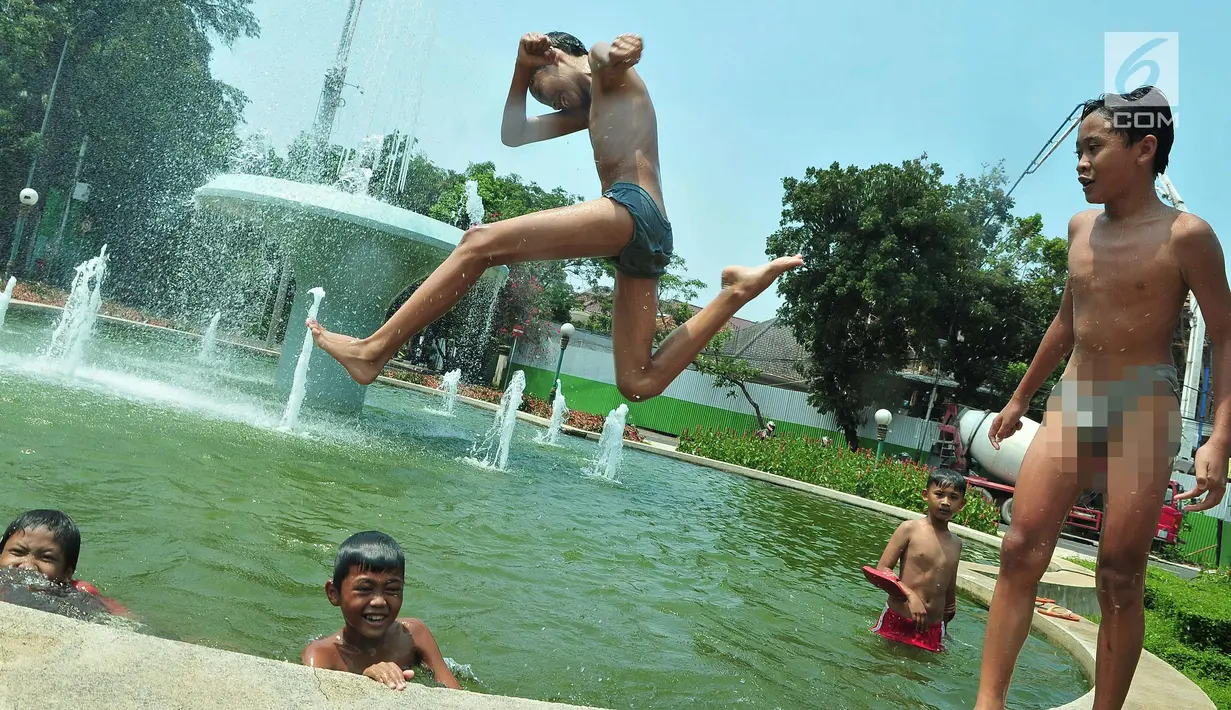 Seorang anak melompat di bundaran air mancur Jalan Teuku Umar, Jakarta Pusat, Sabtu (23/9). Cuaca panas ibu kota memaksa anak-anak menceburkan diri di kolam untuk menyejukkan badan. (Liputan6.com/Helmi Afandi)