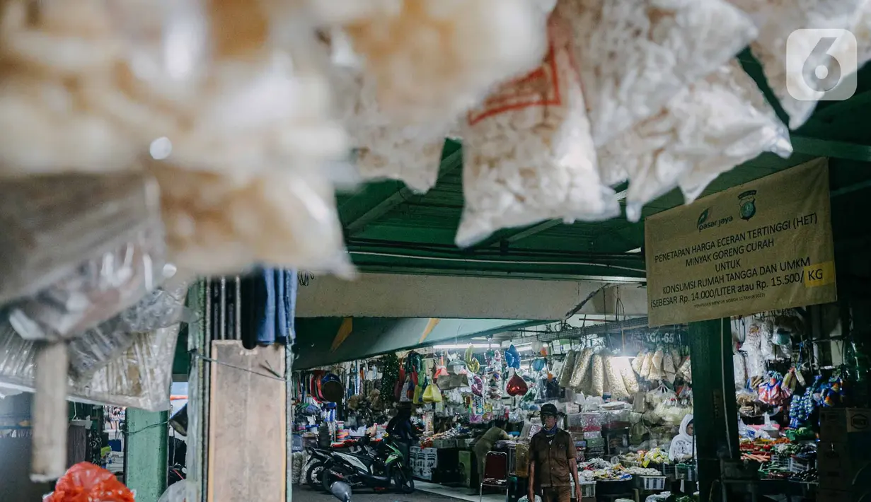 Pedagang melintas di dekat spanduk terkait penetapan harga minyak goreng subsidi di lorong Pasar Kramat Jati, Jakarta, Senin (30/5/2022). Adanya spanduk minyak goreng subsidi tersebut  untuk mensosialisasikan soalnya Per 31 Mei 2022 pemerintah berencana mencabut subsidi minyak goreng curah. (Liputan6.com/Faizal Fanani)