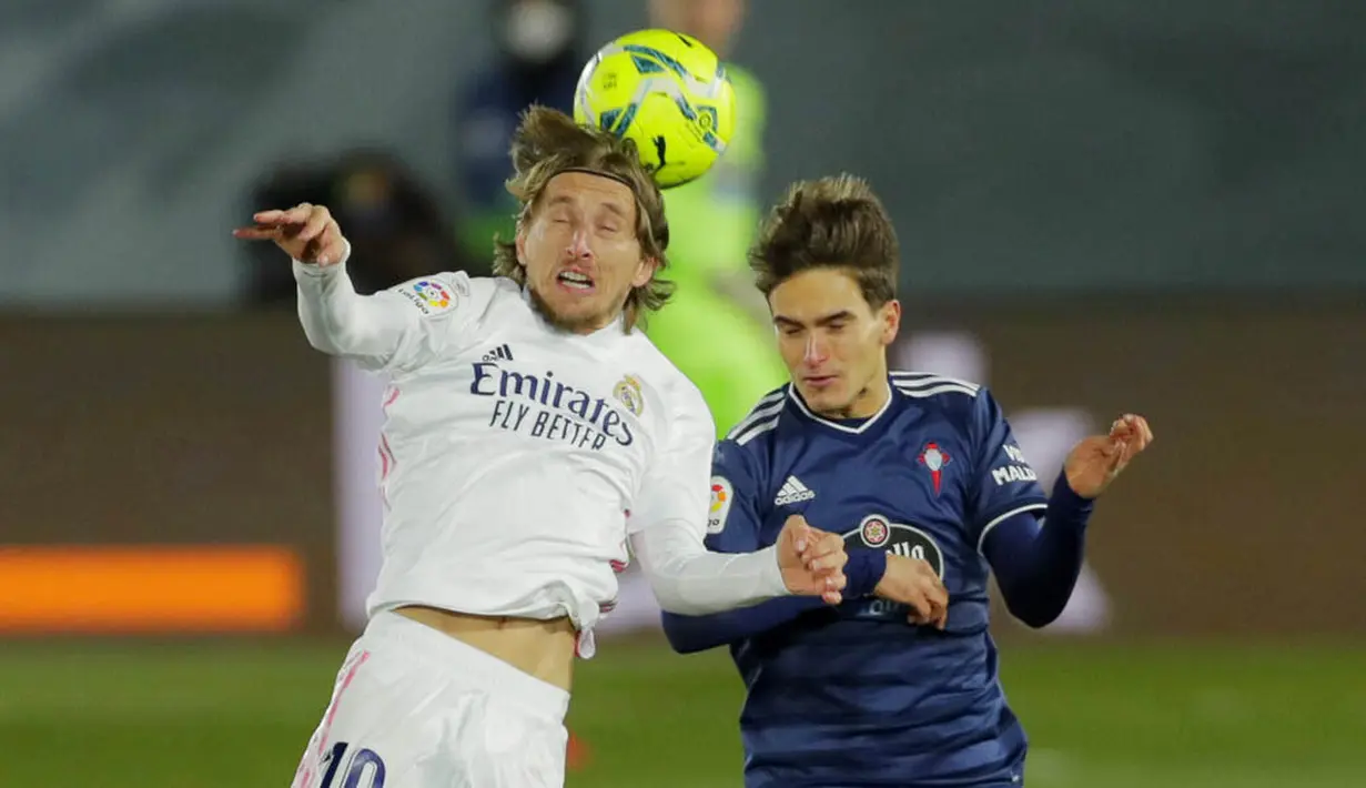 Gelandang Real Madrid, Luka Modric, duel udara dengan pemain Celta Vigo, Denis Suarez, pada laga Liga Spanyol di Stadion Alfredo Di Stefano, Sabtu (2/1/2021). Real Madrid menang dengan skor 2-0. (AP/Manu Fernandez)