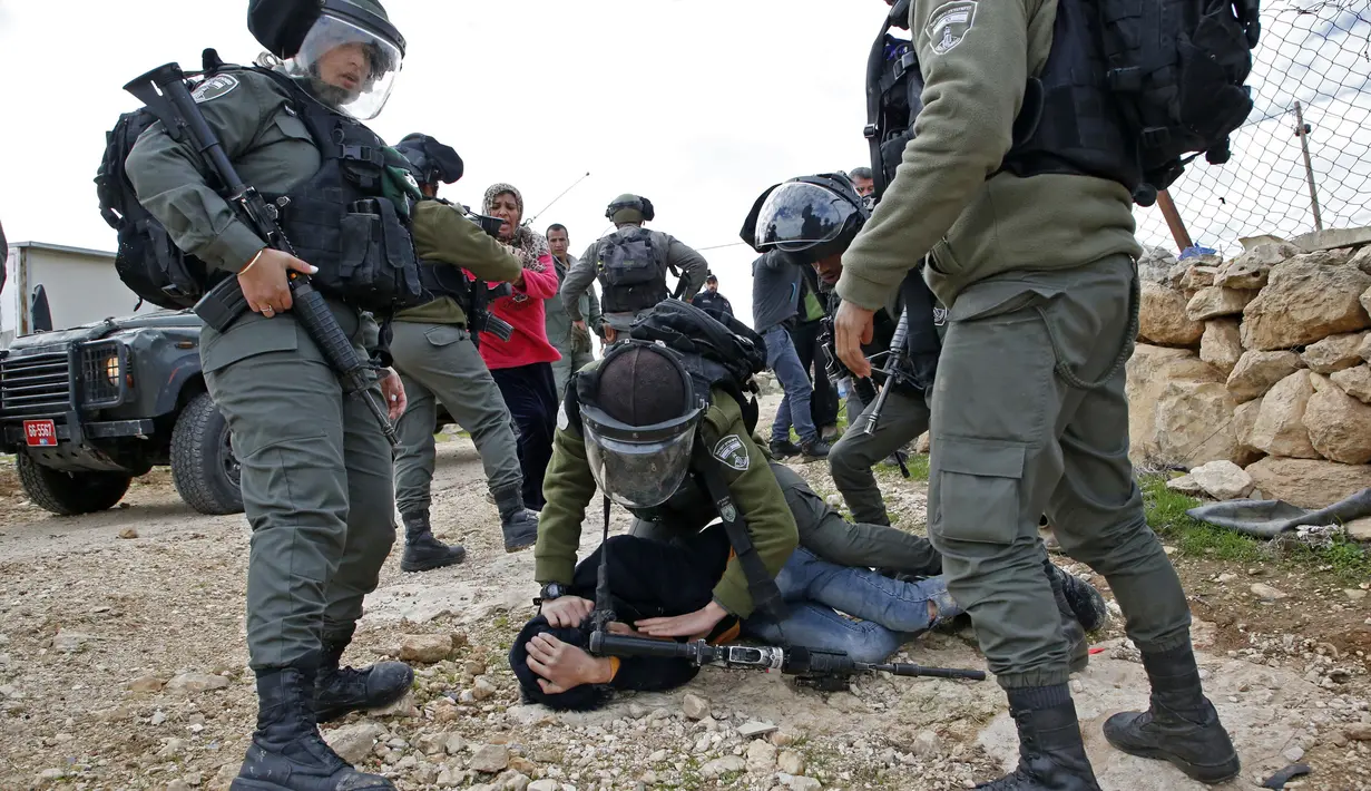 Polisi Israel mengamankan seorang perempuan yang memprotes pembongkaran rumah di Desa Al-Dirat, dekat kota Hebron, Tepi Barat (16/1/2020). Pembongkaran itu menurut otoritas Israel dilakukan karena rumah dibangun tanpa izin. (AFP/Hazem Bader)