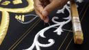 Pekerja menyulam kaligrafi Islam menggunakan benang perak murni pada tahap akhir pembuatan Kiswah Kabah di pabrik Kiswah di Mekah, Arab Saudi, Rabu (14/7/2021). Kiswah yang menutupi Kabah diganti setiap tahun untuk umrah atau haji. (AP Photo/Amr Nabil)