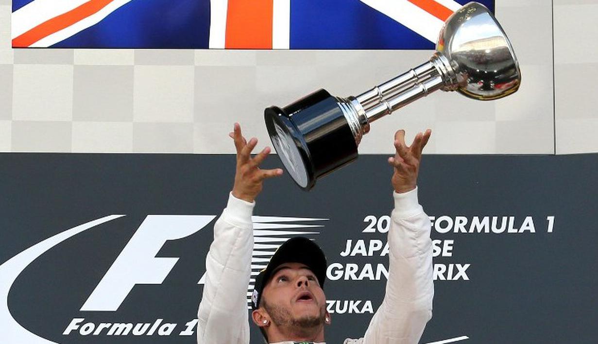 Lewis Hamilton mengangkat trofi juara F1 GP Jepang di Sirkuit Suzuka, Jepang, Minggu (27/9/2015). (AFP Photo/Yuriko Nakao)