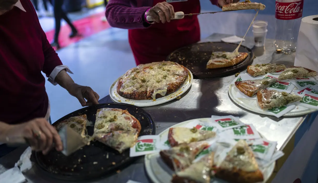 Relawan mengantarkan potongan pizza yang dibuat oleh master pizza selama Kejuaraan Pizza Argentina di Buenos Aires, Argentina, Selasa (7/6/2022). Pemenang yang terpilih sebagai “Great Argentine Champion” akan menjadi bagian dari tim Argentina di Kejuaraan Pizza Dunia 2023 di Parma (Italia). (AP Photo/Rodrigo Abd)