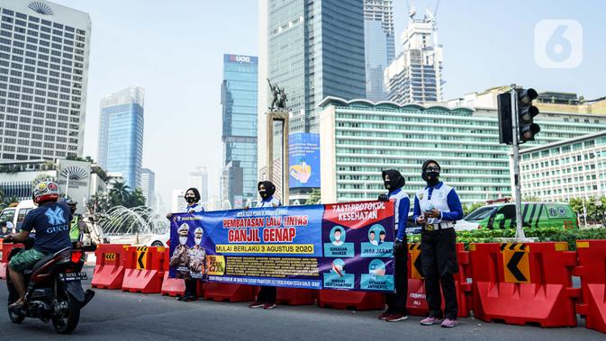 Petugas kepolisian membentangkan spanduk saat sosialisasi pelaksanaan ganjil genap di Kawasan Bundaran HI, Jakarta, Minggu (2/8/2020). Ditlantas Polda Metro Jaya kembali memberlakukan sistem ganjil genap di 25 ruas jalan protokol  DKI Jakarta mulai Senin, 3 Agustus 2020. (Liputan6.com/Faizal Fanani)