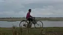 Nelayan mengendarai sepeda di tepi sungai Brahmaputra di Jorhat, Assam, India (3/4). Assam sangat kaya akan sumber daya airnya. Brahmaputra adalah salah satu sungai terbesar di Asia, yang melewati wilayah China Tibet, India dan Bangladesh sebelum konvergen ke Teluk Benggala. (AP Photo/Anupam Nath)