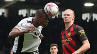 Bek Fulham, Issa Diop menjauhkan bola dari jangkauan penyerang Manchester City, Erling Haaland dalam lanjutan Premier League 2022/2023, Minggu (30/4/2023) malam. (AFP/Adrian Dennis)