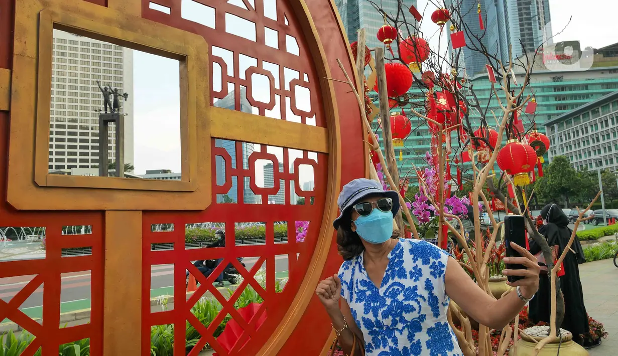 Warga berswafoto di depan ornamen dengan nuansa Imlek di kawasan Bundaran HI, Jakarta, Sabtu (29/1/2022). Ornamen yang didominasi warna merah dan emas ini dipasang dalam rangka menyambut perayaan Tahun Baru Imlek 2573, yang jatuh pada 1 Februari mendatang. (Liputan6.com/Herman Zakharia)