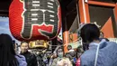 Orang-orang berfoto di kuil Sensoji menjelang liburan Tahun Baru di Tokyo pada 30 Desember 2022. Kuil Sensoji dikenal sebagai tempat wisata paling terkenal di Tokyo. (AFP/Yuichi Yamazaki)