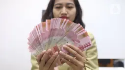 Pegawai menunjukkan mata uang rupiah di penukaran uang di Jakarta, Rabu (4/3/2020). Rupiah ditutup menguat 170 poin atau 1,19 persen menjadi Rp14.113 per dolar AS dibandingkan posisi hari sebelumnya Rp14.283 per dolar AS. (Liputan6.com/Angga Yuniar)