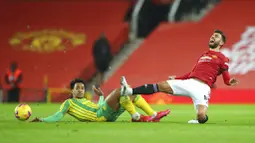 Gelandang Manchester United, Bruno Fernandes, meringis kesakitan saat berebut bola dengan pemain West Bromwich Albion, Matheus Pereira, pada laga Liga Inggris di Stadion Old Trafford, Minggu (22/11/2020). MU menang dengan skor 1-0. (Alex Livesey/Pool via AP)
