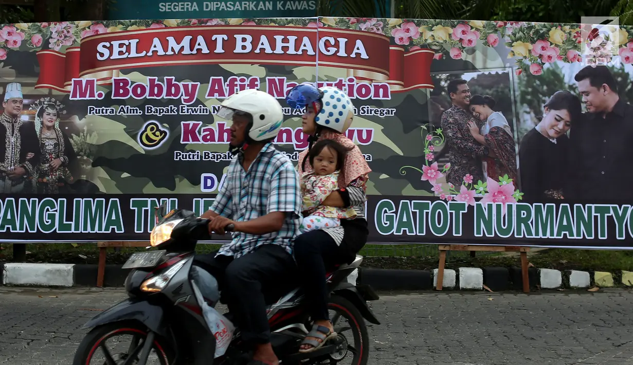 Warga melintas di depan karangan bunga dan ucapan selamat untuk Kahiyang-Bobby yang terpampang di pinggir jalan Komplek Bukit Hijau Regency (BHR), Medan, Kamis (23/11). (Liputan6.com/JohanTallo)