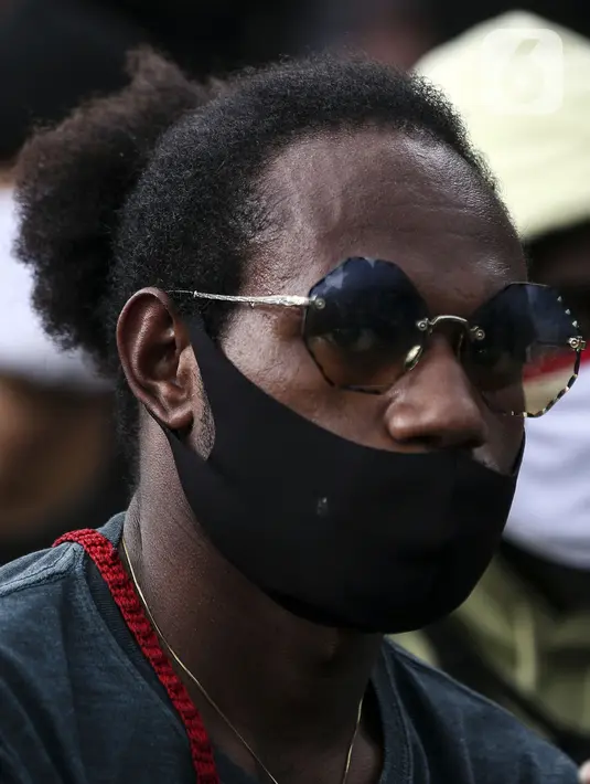 Masyarakat Papua mengenakan masker saat memperingati Operasi Trikora 19 Desember 1961 di Patung Kuda, Jakarta, Sabtu (19/12/2020). Salah satu tuntutan massa adalah penghentian segala bentuk diskriminasi dan intimidasi terhadap mahasiswa Papua Barat. (Liputan6.com/Johan Tallo)