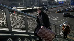 Seorang wanita membawa koper melewati jembatan penyeberangan di luar stasiun kereta api Beijing, Jumat (10/1/2020). Puluhan ribu warga China telah memulai migrasi manusia terbesar di dunia meninggalkan kota-kota besar menuju kampung halaman untuk merayakan Tahun Baru Imlek. (WANG ZHAO/AFP)