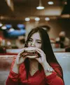Ilustrasi perempuan makan burger/copyright unsplash.com/Hector Gomez