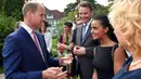 Pangeran William berbincang dengan para tamu saat acara 'Queen's Birthday Garten Party' di kediaman duta besar Inggris di Berlin, Rabu (19/7). Melengkapi gaya berbusana pasangannya, William mengenakan setelan jas dan dasi merah (Jens Kalaene/dpa via AP)