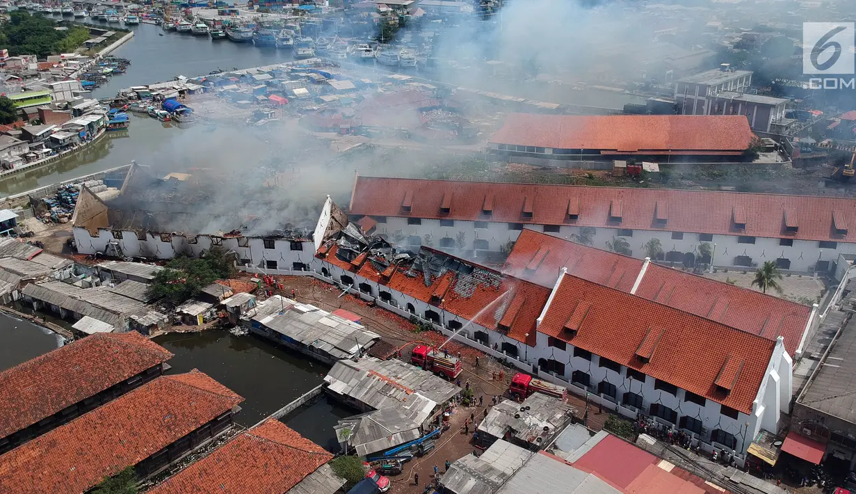 Foto udara menunjukkan petugas pemadam kebakaran memadamkan sisa api yang membakar Museum Bahari, Jakarta Utara, Selasa (16/1). Untuk menjinakan api, petugas pemadam kebakaran mengerahkan 21 unit mobil pemadam. (Liputan6.com/Arya Manggala)