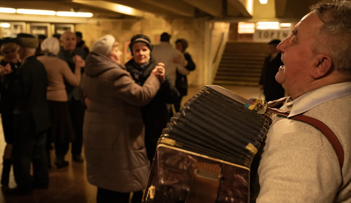 Sepasang lansia menari di Stasiun Kereta Bawah Tanah Teatralna, Kiev, Ukraina, 5 Maret 2023. Puluhan pensiunan menari selama lebih dari dua jam dalam acara akhir pekan yang telah berlangsung selama puluhan tahun dan hanya sempat terganggu oleh invasi Rusia ke Ukraina. (AP Photo/Vadim Ghirda)