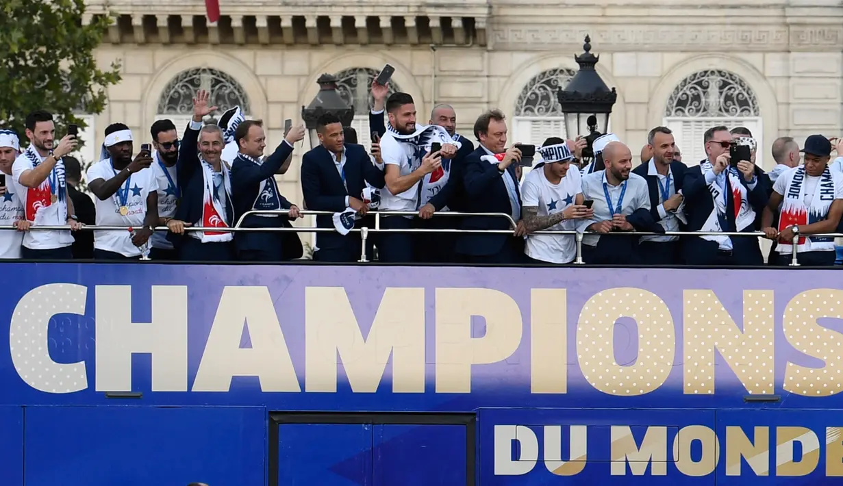 Timnas Prancis mengikuti pawai dengan bus atap terbuka merayakan juara Piala Dunia 2018 di jalan Champs Elysees, Paris, Senin (16/7). Prancis menggelar pesta besar penyambutan sekaligus parade kemenangan bagi skuad Les Bleus. (Eric Feferberg/Pool via AP)