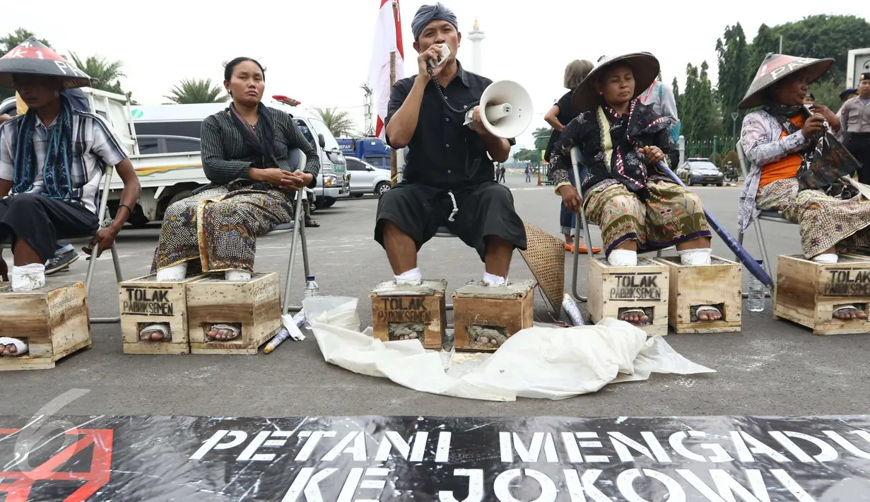 Seorang pria dari Petani Kendeng, Pati yang kakinya disemen berorasi saat menggelar aksi di depan Istana Negara, Jakarta, Selasa (14 /3). (Liputan6.com/Helmi Afandi)